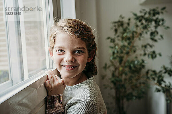 Happy cute girl by window at home