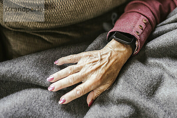Hand einer älteren Frau mit intelligenter Uhr über der Decke