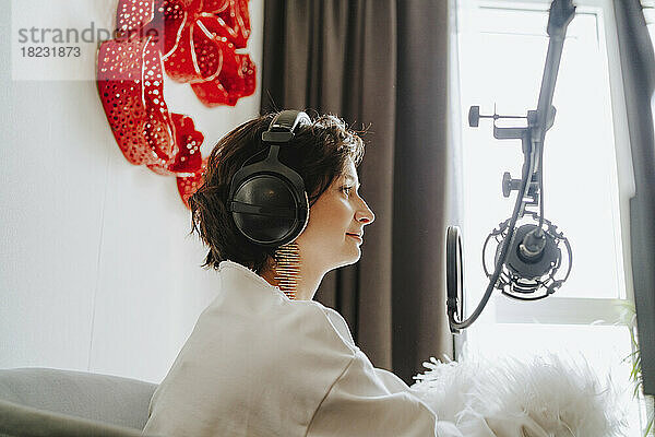 Lächelnder Musiker vor dem Mikrofon im Studio