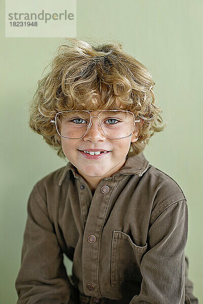 Smiling boy wearing eyeglasses against green background