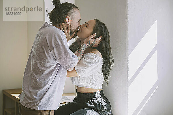 Romantisches Hipster-Paar küsst sich vor der Wand