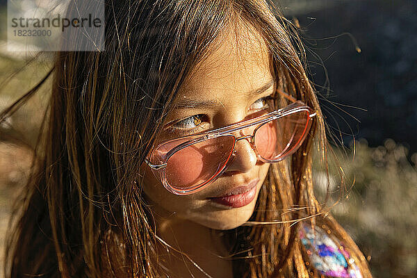 Mädchen mit Sonnenbrille schaut an einem sonnigen Tag weg