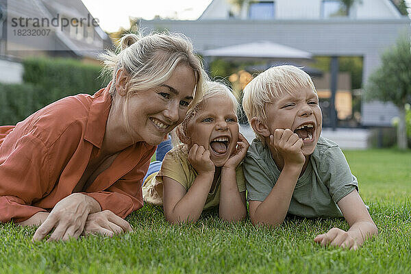Glückliche Frau mit Mädchen und Jungen  die sich im Hinterhof auf die Ellbogen stützen