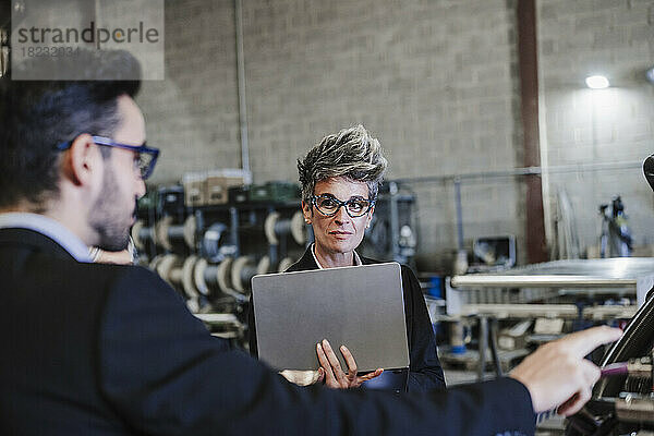 Reife Geschäftsfrau mit Tablet-PC diskutiert über Maschinen in der Industrie