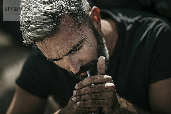 Mature man with beard igniting cigarette