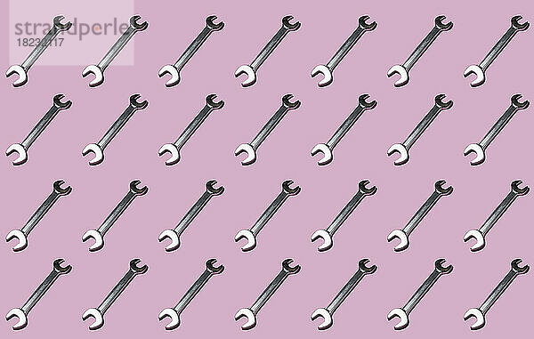 Pattern of rows of wrenches flat laid against pink background
