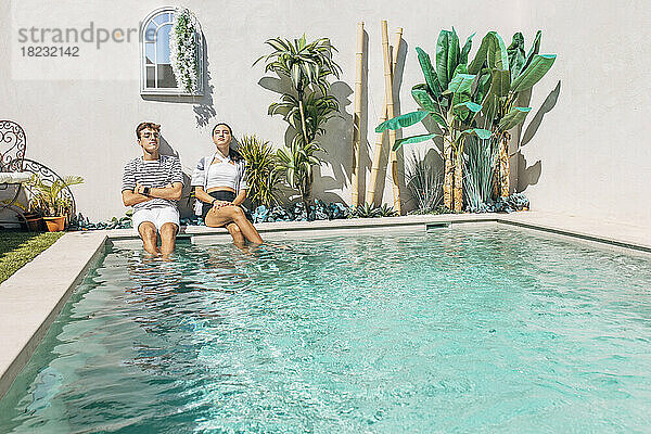 Bruder und Schwester entspannen sich an einem sonnigen Tag am Pool