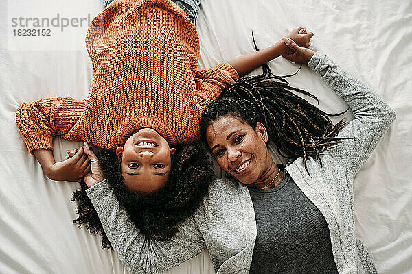 Happy mother and daughter relaxing on bed at home