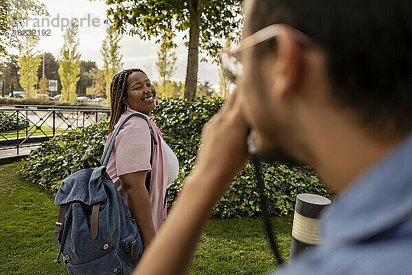 Young man photographing curvy woman at park