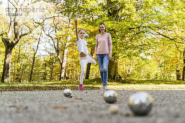 Glückliche Mutter und Tochter spielen Boule im Park