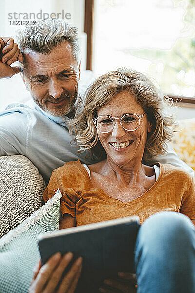 Glückliche Frau mit Brille und Mann zu Hause mit Tablet-PC
