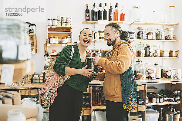 Glücklicher Mann und Frau mit Einmachglas im Null-Abfall-Laden