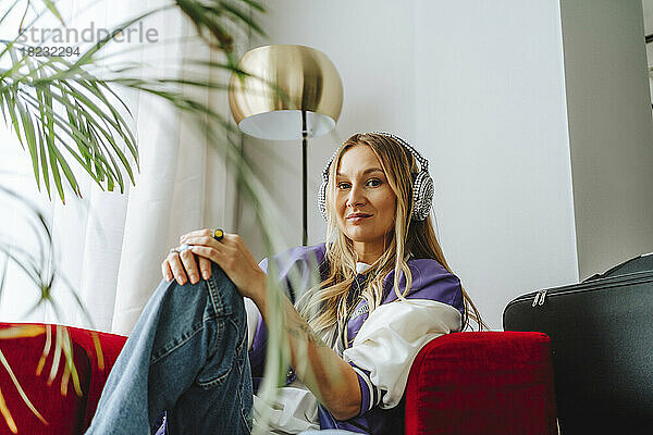 Woman wearing headphones on armchair in studio
