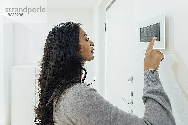 Frau benutzt Smart-Home-Gerät an der Wand