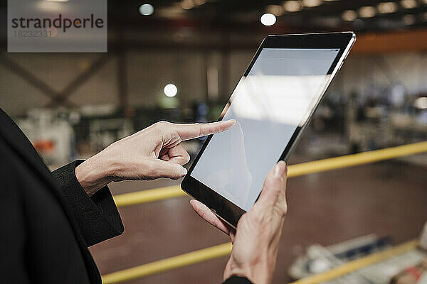 Hand einer Geschäftsfrau  die in der Fabrik einen Tablet-PC verwendet