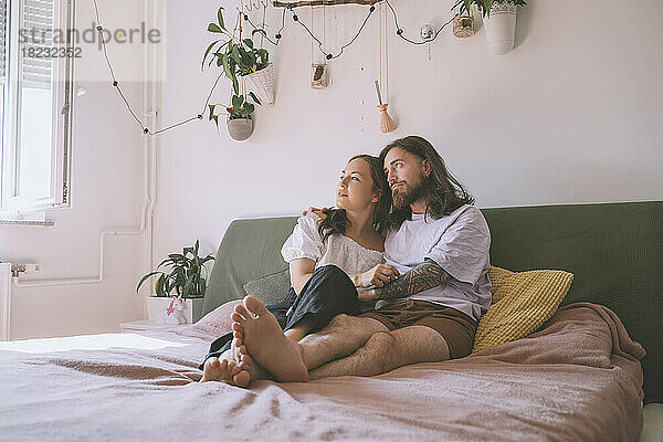 Nachdenkliches Hipster-Paar sitzt zu Hause im Bett