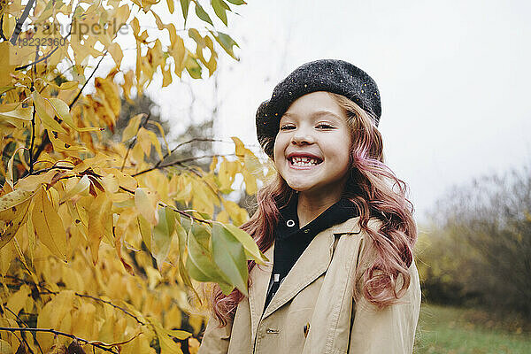 Glückliches süßes Mädchen mit Baskenmütze  das im Herbstpark steht