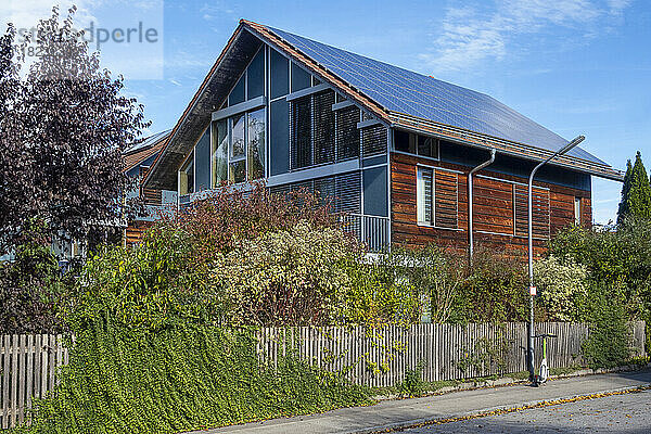 Deutschland  Bayern  München  Überwucherter Zaun rund um ein modernes Passivhaus mit Sonnenkollektoren