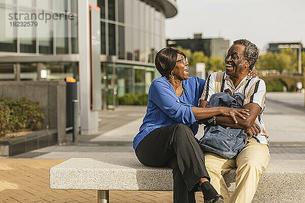 Älteres Paar lacht miteinander und sitzt auf einer Bank