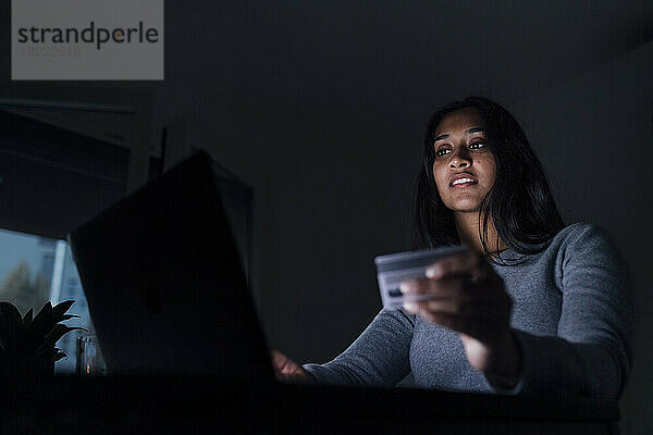 Junge Frau mit Kreditkarte beim Online-Shopping per Laptop zu Hause