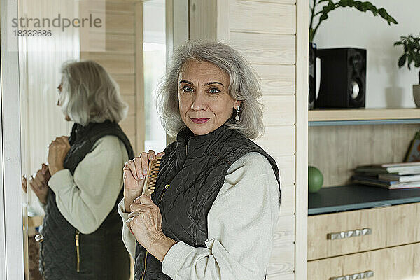Porträt einer selbstbewussten älteren Frau vor dem Spiegel zu Hause