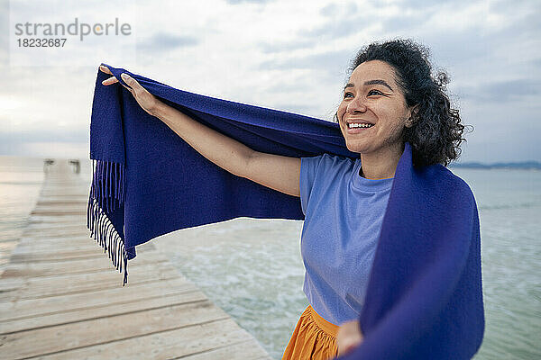 Glückliche Frau  die inmitten des Meeres einen Schal einwickelt