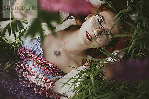 Teenage girl lying on grass with lupin flowers