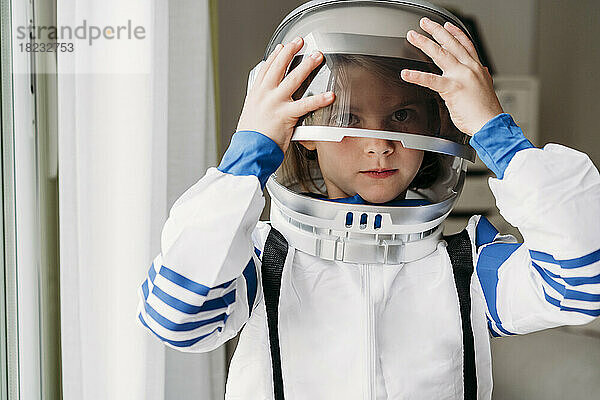 Girl wearing space helmet at home