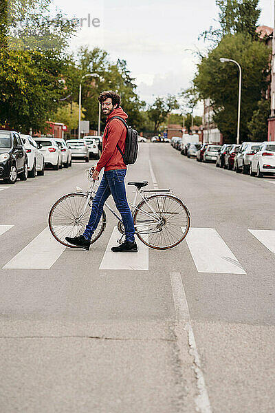 Mann überquert Straße mit Fahrrad in der Stadt