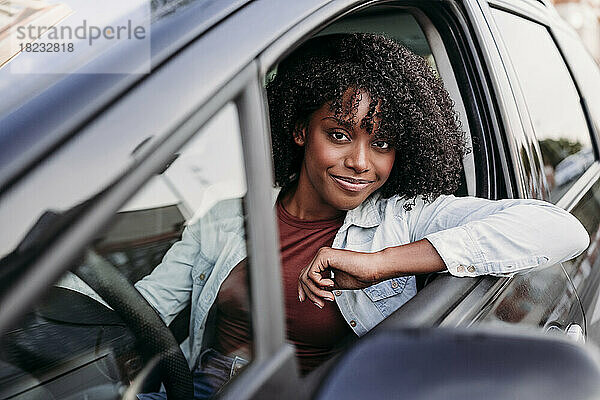 Lächelnde Frau mit lockigem Haar sitzt im Auto