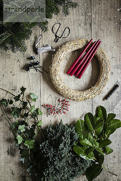 Preparation of Christmas wreath made of spruce  juniper  ivy  rose hips and candles