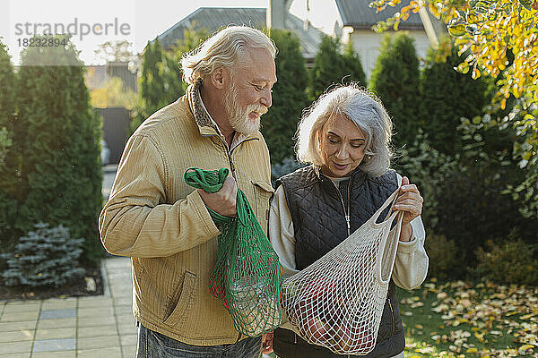 Älteres Paar trägt Lebensmittel in umweltfreundlichen wiederverwendbaren Netzbeuteln