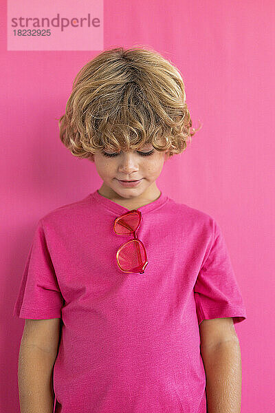 Boy looking down against pink background