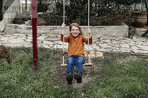Playful girl playing on swing in garden
