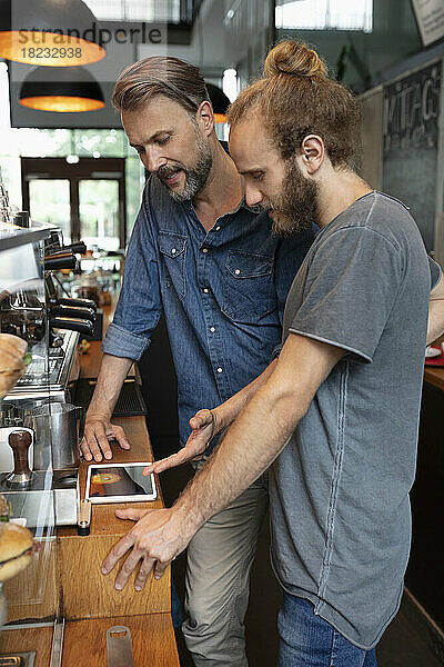 Coffeeshop-Besitzer teilt Tablet-PC mit Barista im Café
