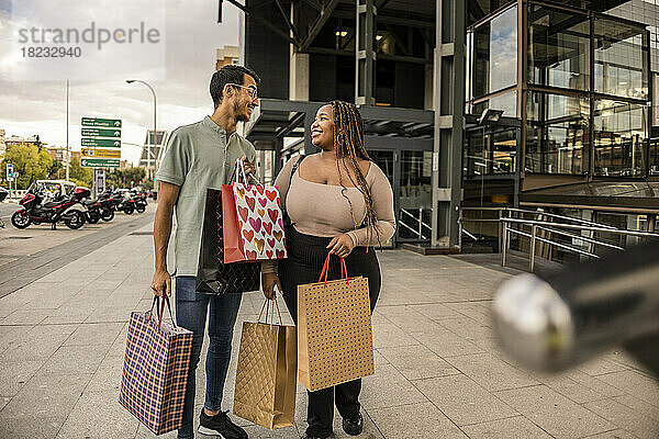 Glückliches junges Paar steht mit Einkaufstüten auf dem Fußweg