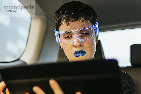 Frau mit Smart-Brille und Tablet-PC im Auto