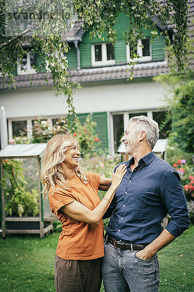 Fröhliche reife Frau steht mit Mann vor dem Haus