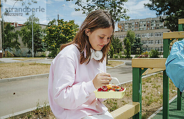 Mädchen isst an einem sonnigen Tag Essen aus der Lunchbox