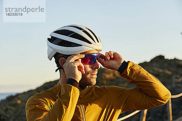 Radfahrer mit Helm und Schutzbrille steht an einem sonnigen Tag