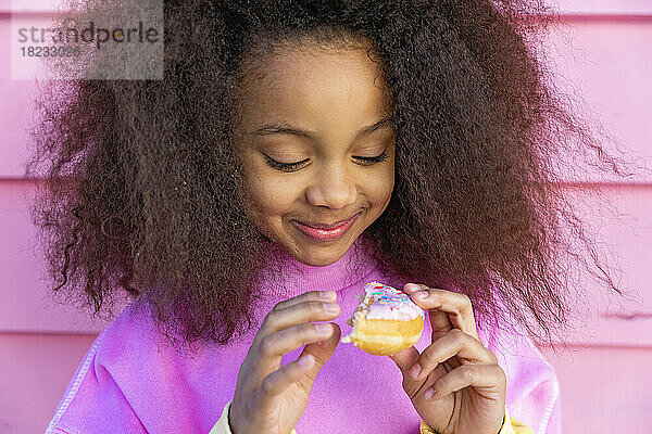 Lächelndes Mädchen  das Donut betrachtet