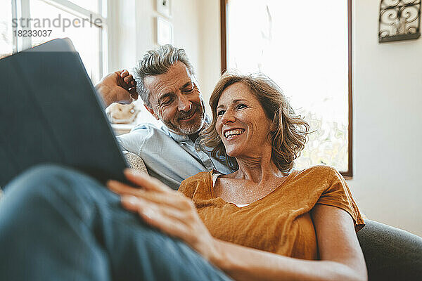 Glücklicher reifer Mann und Frau mit Tablet-PC im Wohnzimmer
