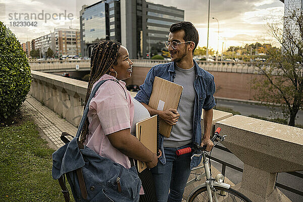 Glückliches junges Paar  das mit dem Fahrrad vor dem Geländer steht