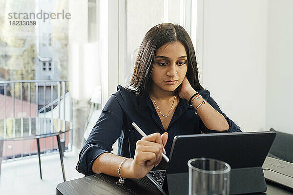 Frau lernt zu Hause mit Tablet-PC am Tisch