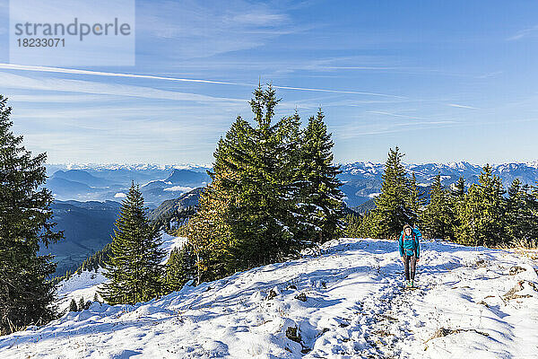 Germany  Bavaria  Female hiker walking through snow-covered mountaintop in Chiemgau Alps