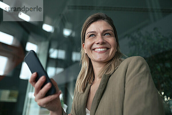 Fröhliche blonde Geschäftsfrau mit Smartphone