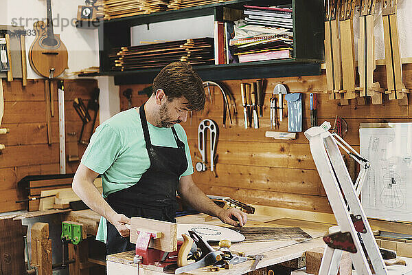 Gitarrenbauer arbeitet in Werkstatt an Gitarrenschablone