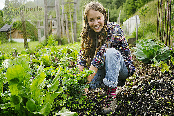 Glückliche junge Frau pflanzt Gemüse im Garten