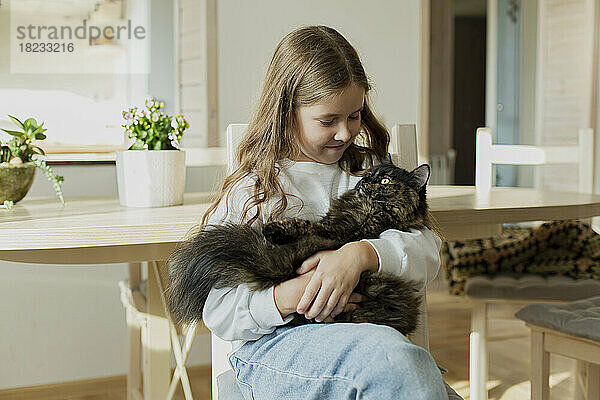 Girl holding a cat at home