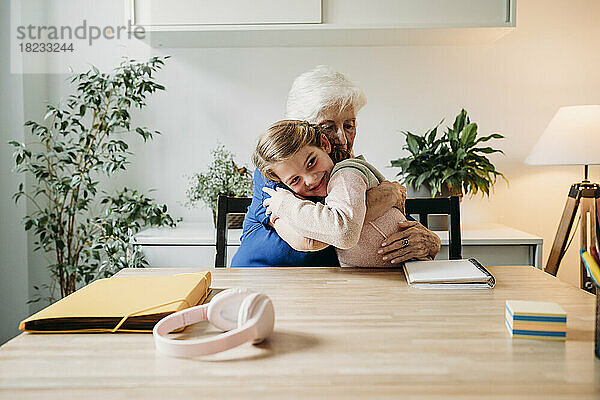 Glückliches Mädchen  das Großmutter zu Hause umarmt